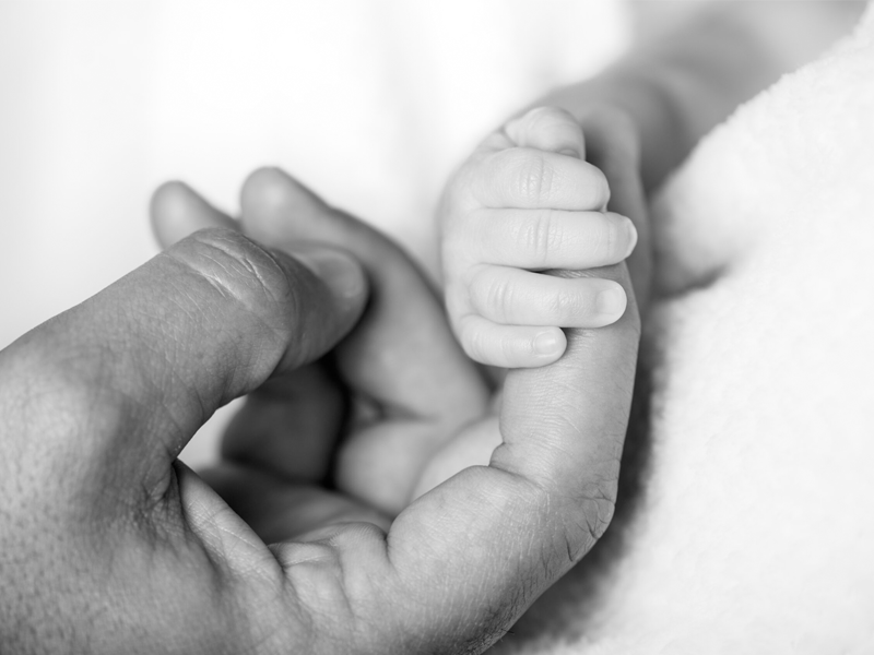 Emmeline holding her dad's finger, shortly after her birth.